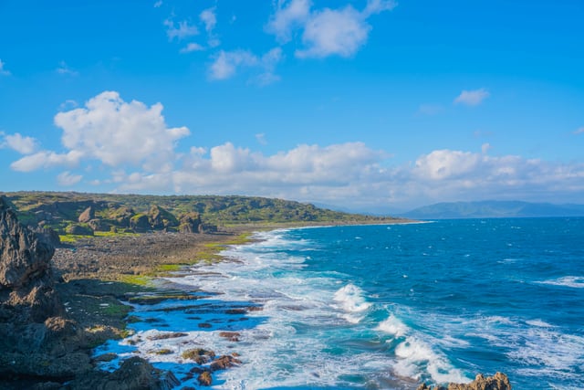 Breathtaking aerial view of Taiwan's rocky coastline with azure sea and white clouds, capturing nature's beauty.