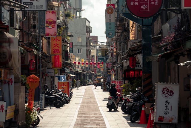 Bustling urban street with scooters and colorful signs in New Taipei City, Taiwan.