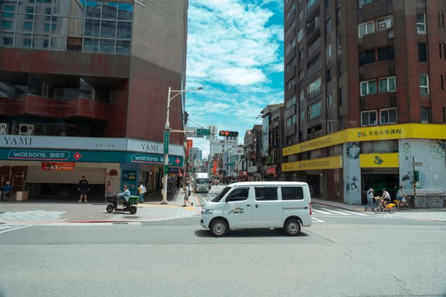Bustling Taipei city street with vehicles and pedestrians, showcasing urban life in Taiwan.