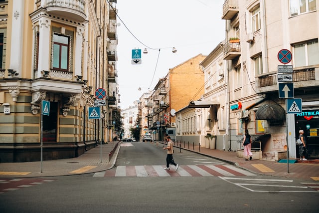Pedestrians cross a street in Kyiv, Ukraine, amidst historic architecture.
