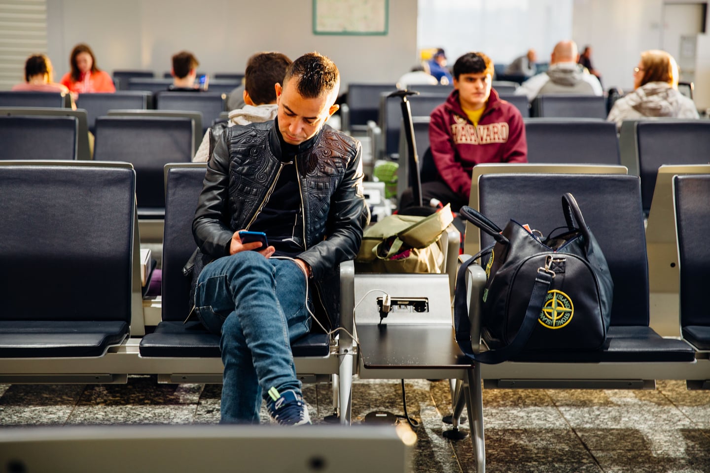 A traveller seated in an airport lounge using a smartphone before a flight.