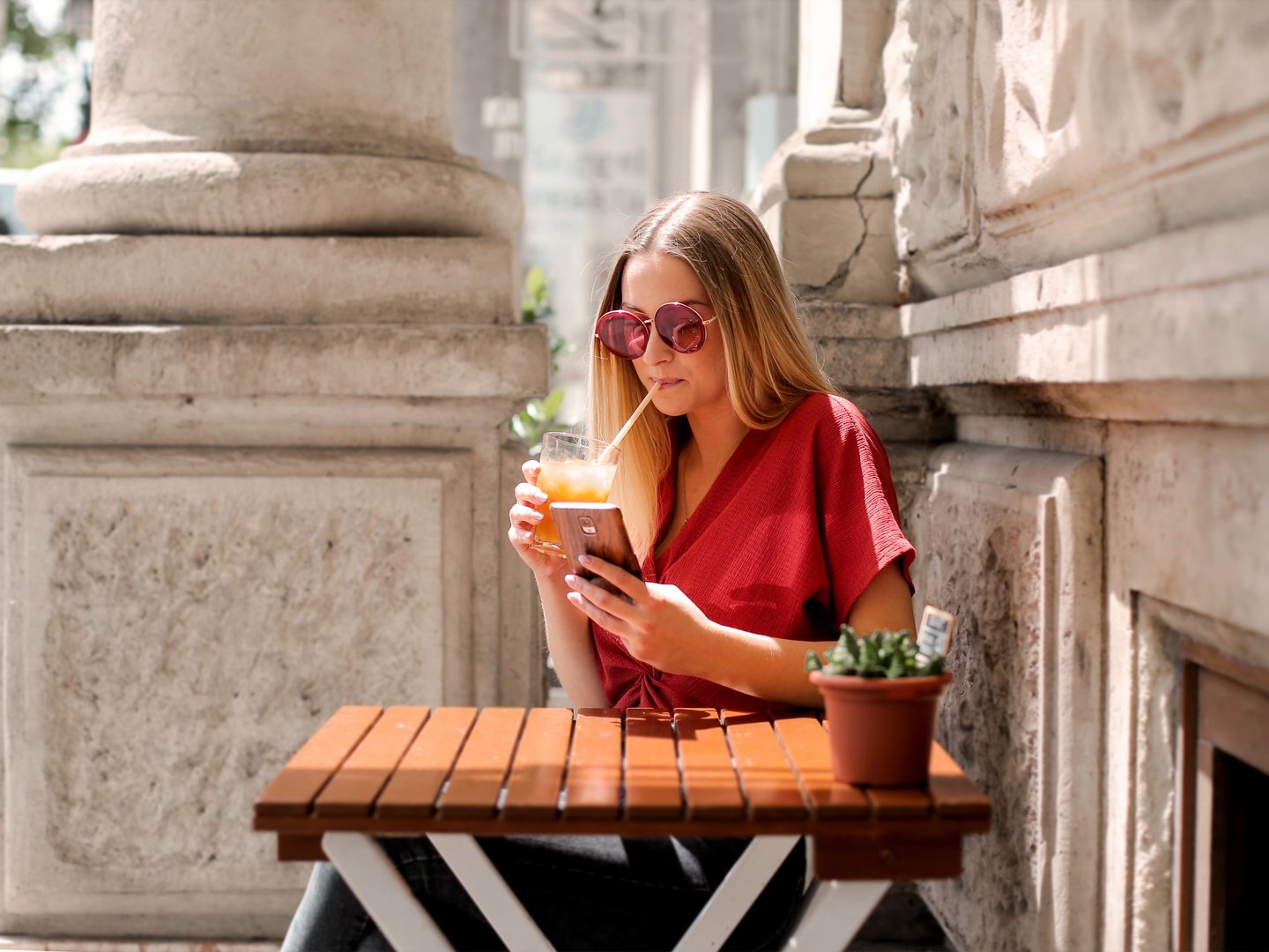 Traveler relaxing at an outdoor cafe terrace and using a smartphone