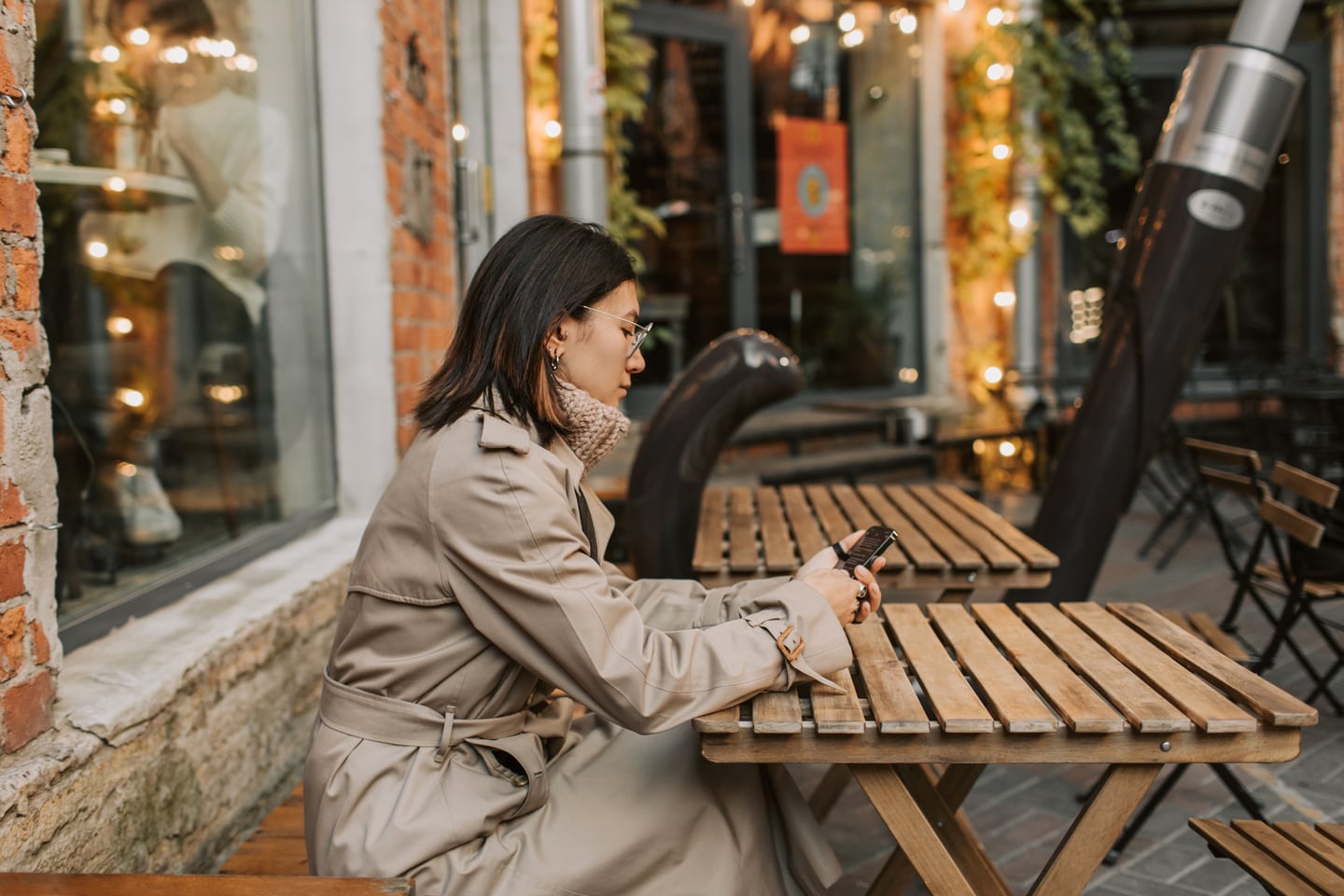 A traveller checking her smartphone at an outdoor café table.