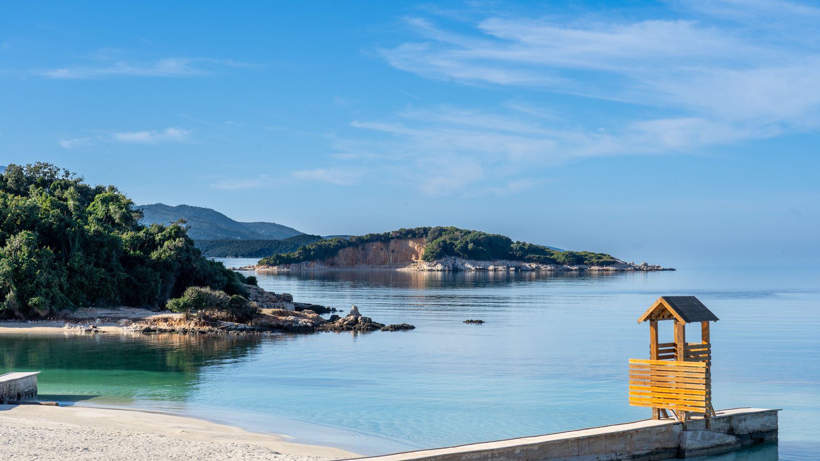 Beautiful beach with clear waters and lush greenery in Ksamil, Albania.