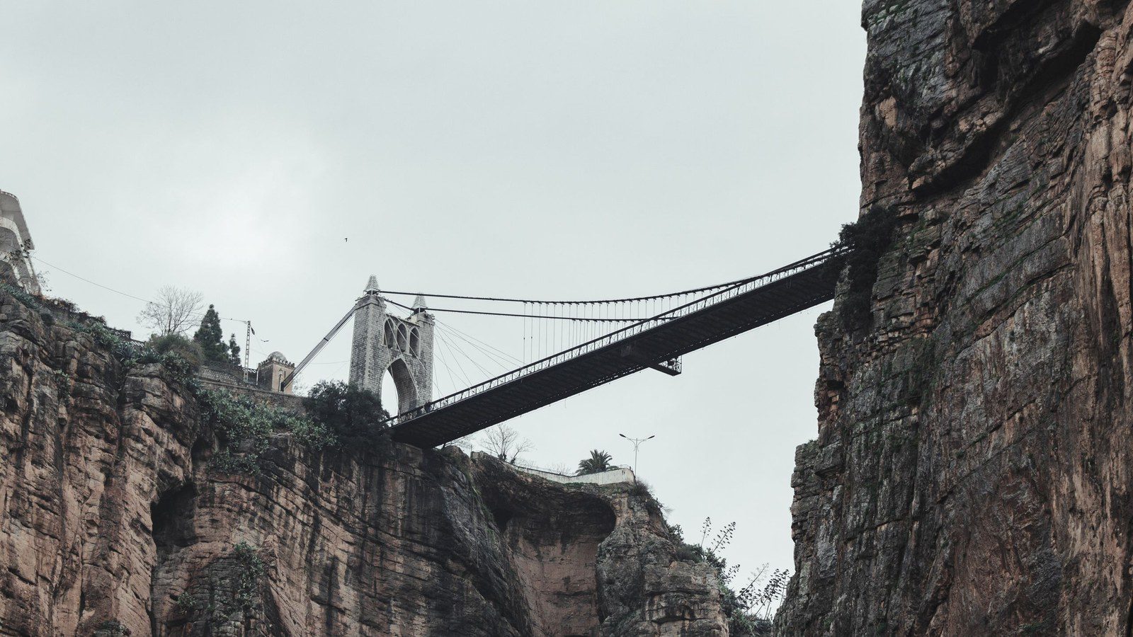 Dramatic suspension bridge spanning high above a deep rocky canyon gorge in Constantine, Algeria