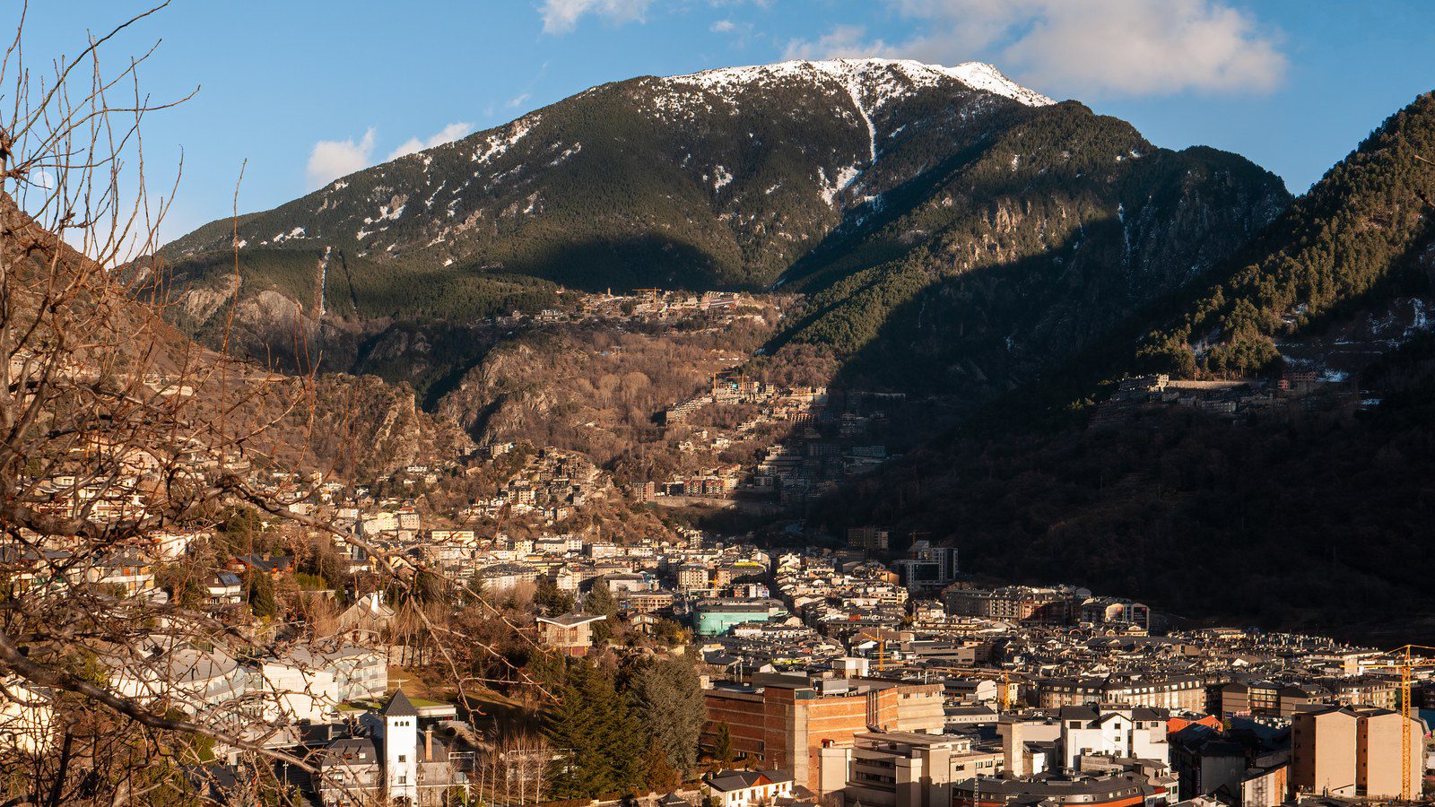 Panoramic view over the town of Andorra la Vella nestled in the Pyrenees mountain valley under snow-capped peaks