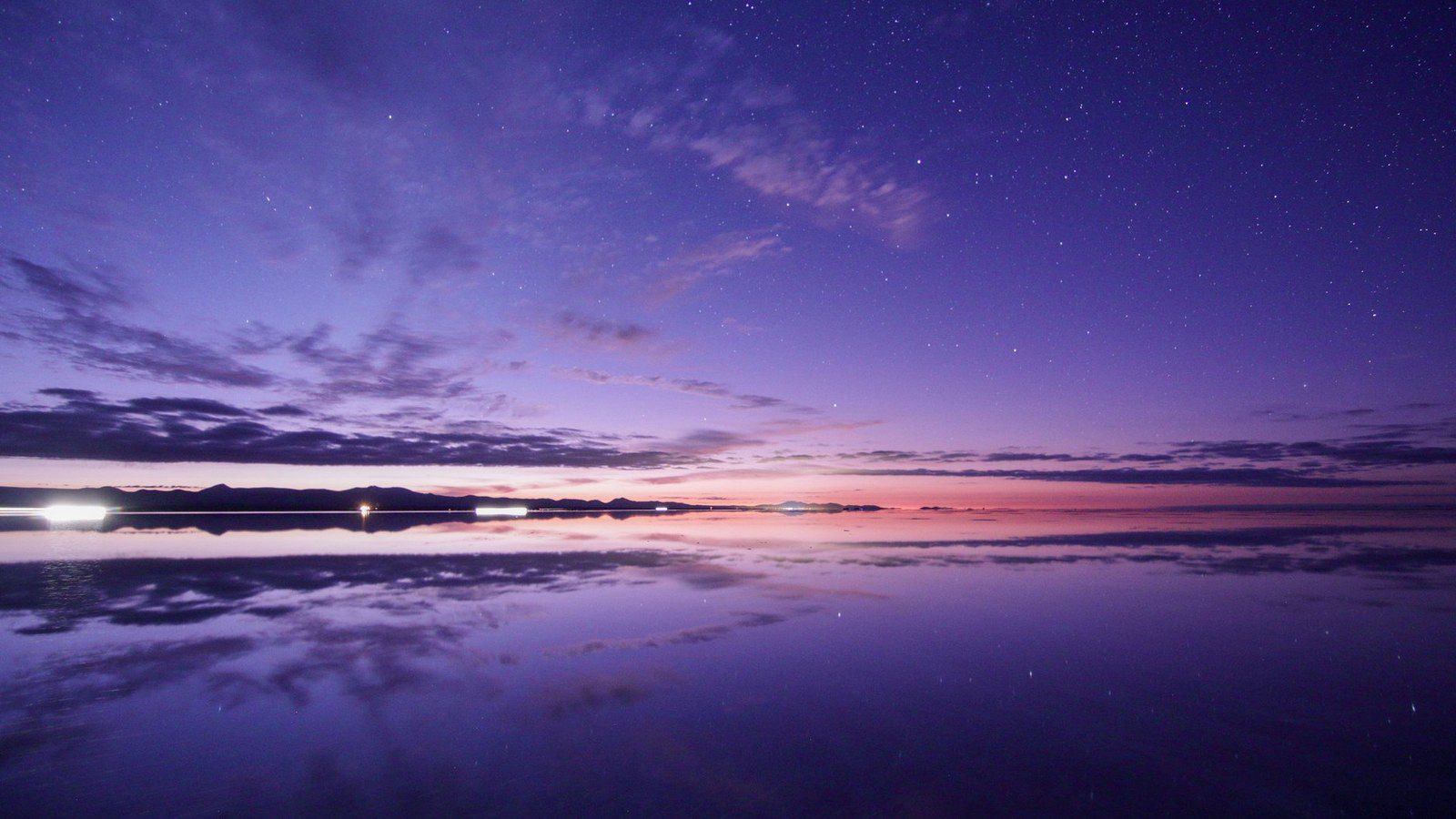 Vast white expanse of the Salar de Uyuni salt flat with distinct geometric hexagonal salt crust patterns reaching toward the horizon in Bolivia