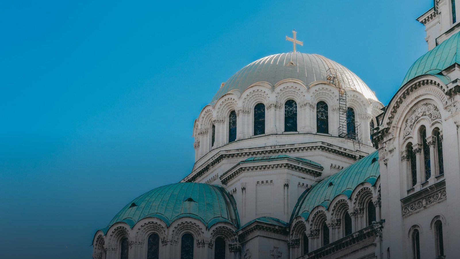 Exterior view of Alexander Nevsky Cathedral in Sofia featuring neo-Byzantine gilded and copper domes under a daylight sky
