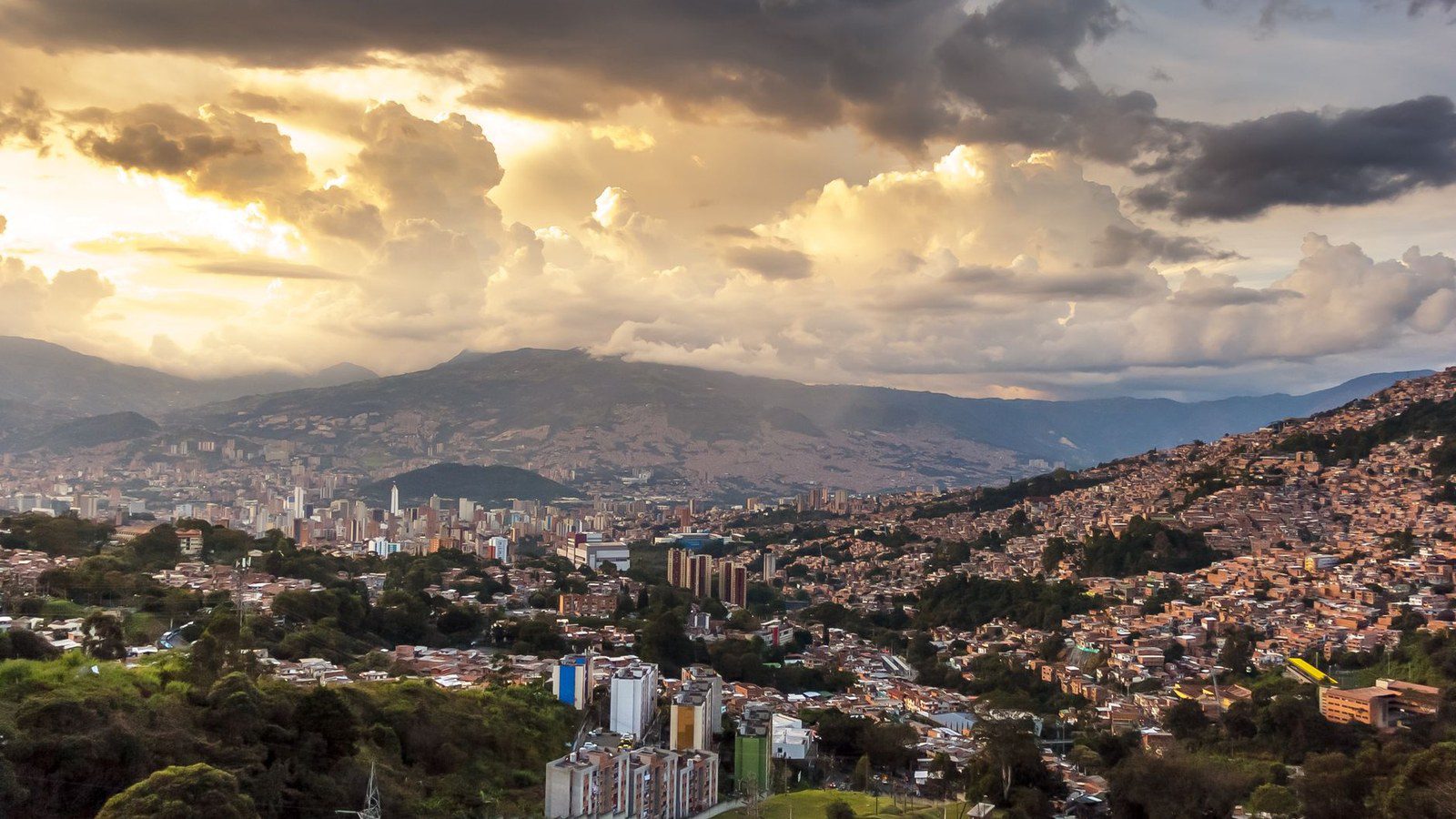Breathtaking view of Medellin's skyline at sunset with dramatic clouds and vibrant colors.