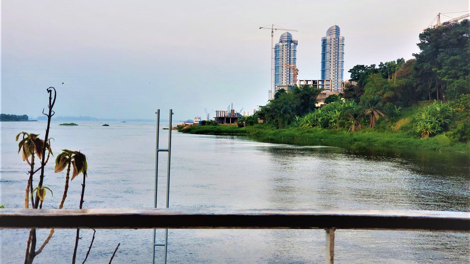 Panoramic view of the wide Congo River flowing past Kinshasa riverbank with distant skyline of Brazzaville in DR Congo