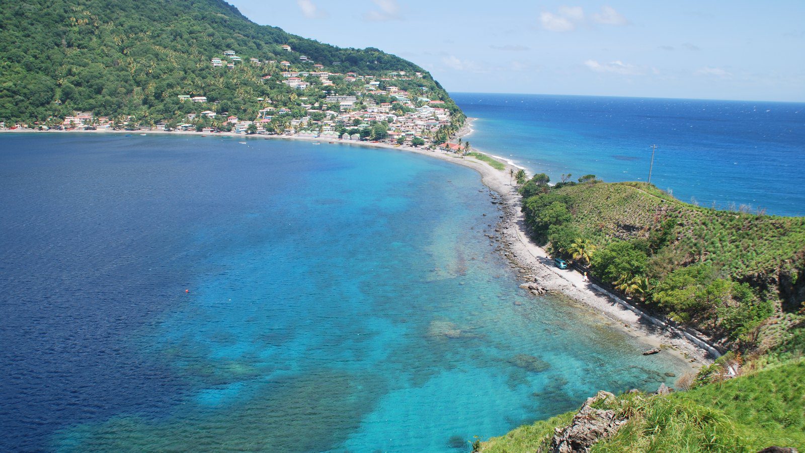 Scenic travel view of volcanic peninsula and coastal village at Scott's Head, Dominica