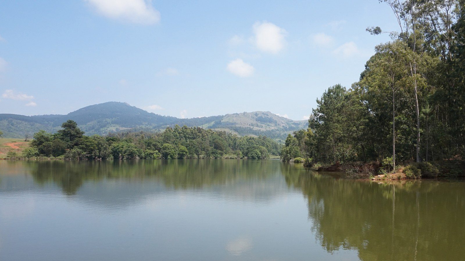 Tranquil lake and wooden boardwalk surrounded by green mountain peaks in Mlilwane Wildlife Sanctuary, Eswatini