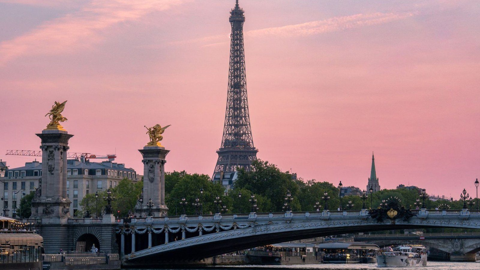 Eiffel Tower illuminated against a sunset sky above the River Seine in Paris