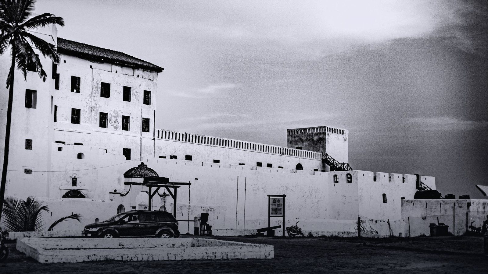 Whitewashed stone walls and historic cannons of Cape Coast Castle overlooking the Atlantic Ocean surf in Ghana