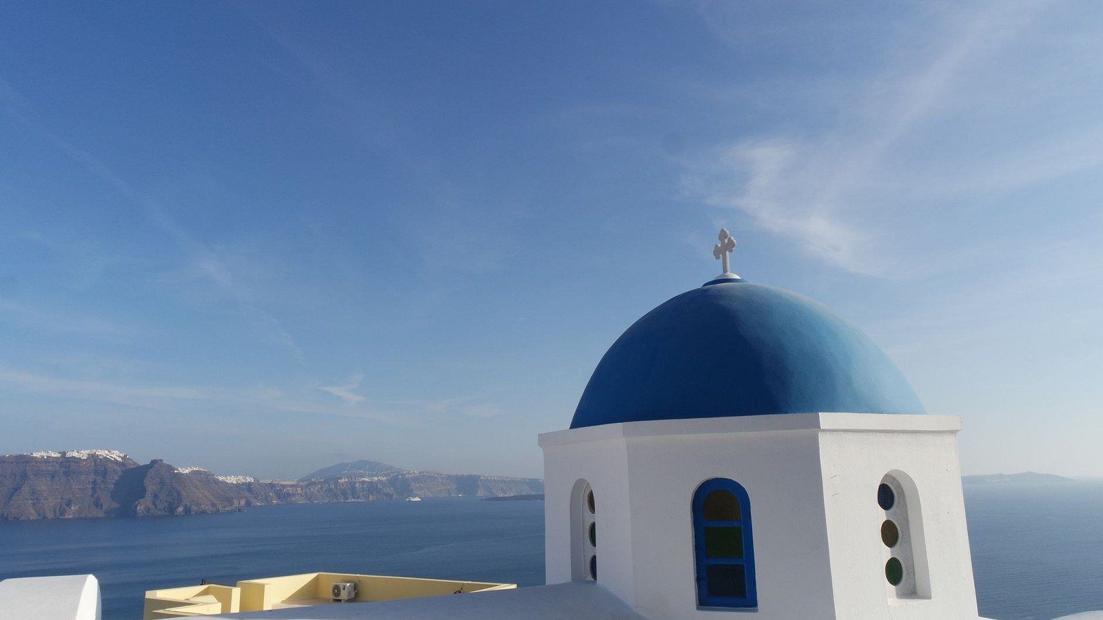 Whitewashed houses and iconic blue-domed church overlooking the volcanic Santorini caldera
