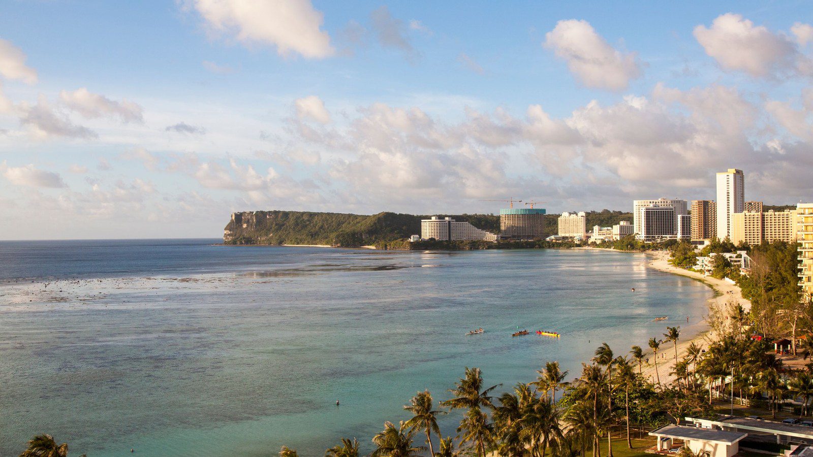 Aerial panoramic view of Tumon Bay coastline with turquoise waters and beachfront resorts in Guam