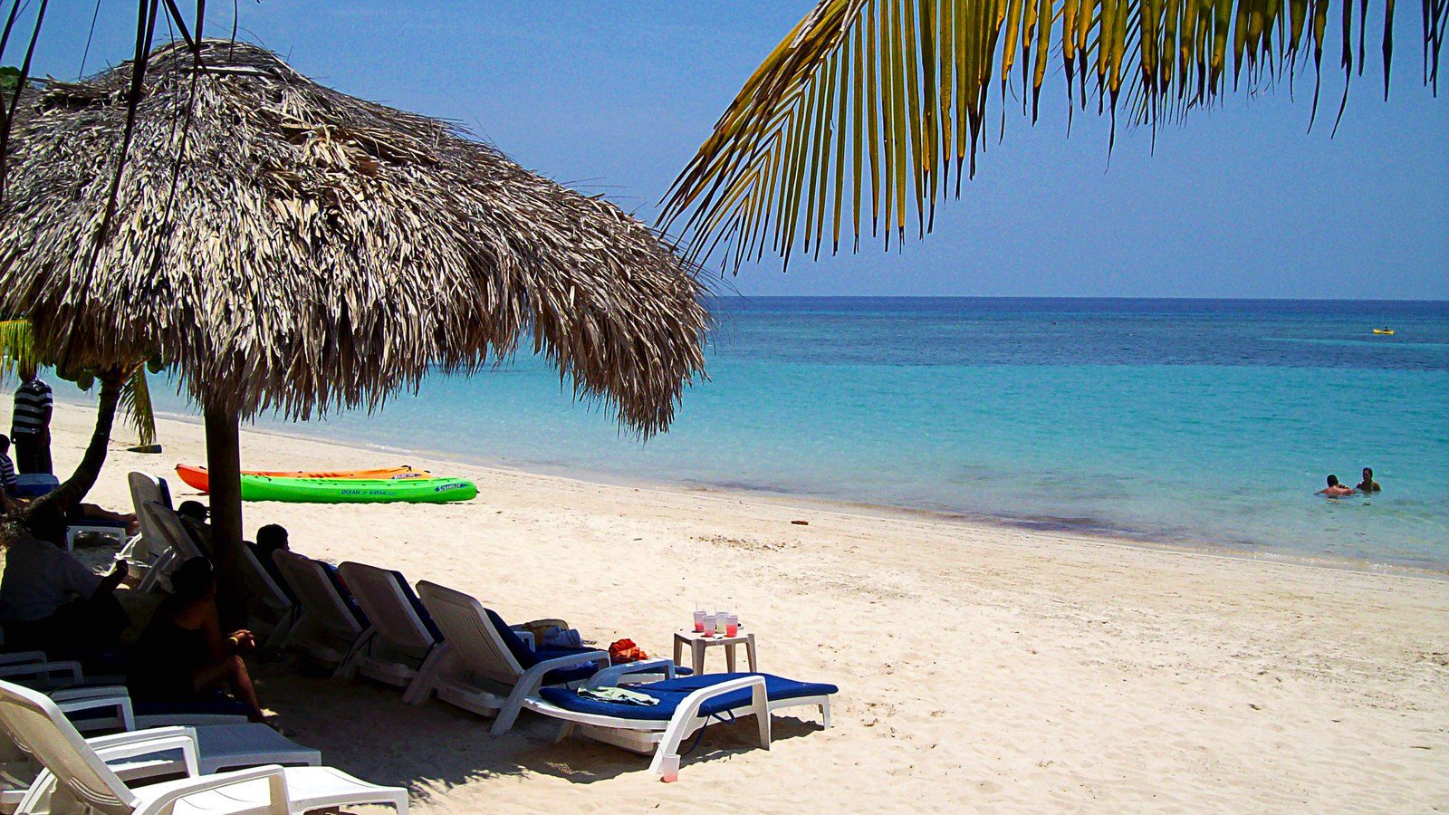 White sand beach, thatched palapa umbrellas, and turquoise Caribbean waters at West Bay on Roatán Island, Honduras
