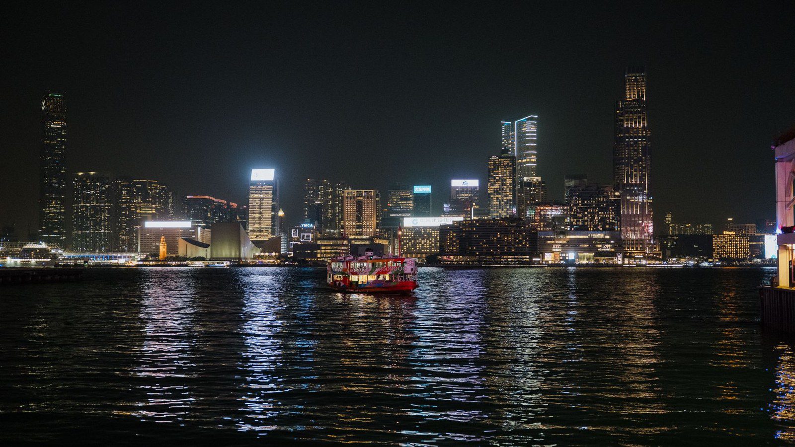 Captivating view of Hong Kong skyline illuminated at night with ferries on Victoria Harbour.