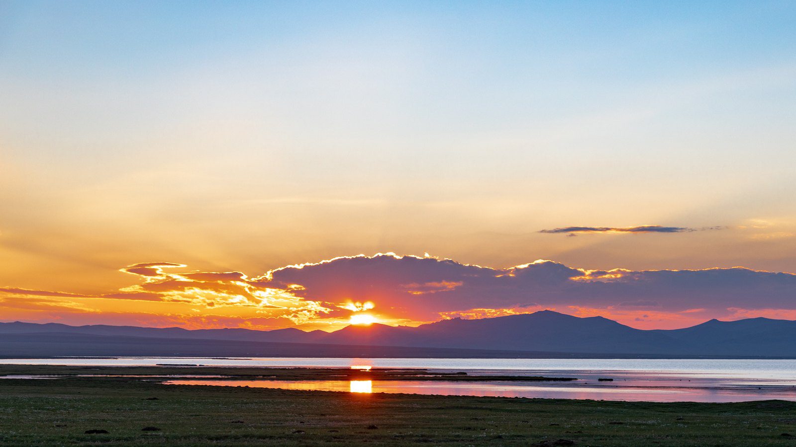 Scenic travel view of alpine pasture and nomadic yurts at Lake Song-Kul, Kyrgyzstan