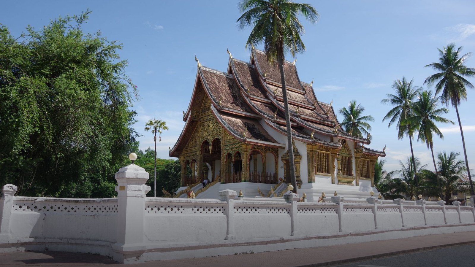 Low sweeping curved roof and gilded glass mosaic exterior of Wat Xieng Thong temple in Luang Prabang