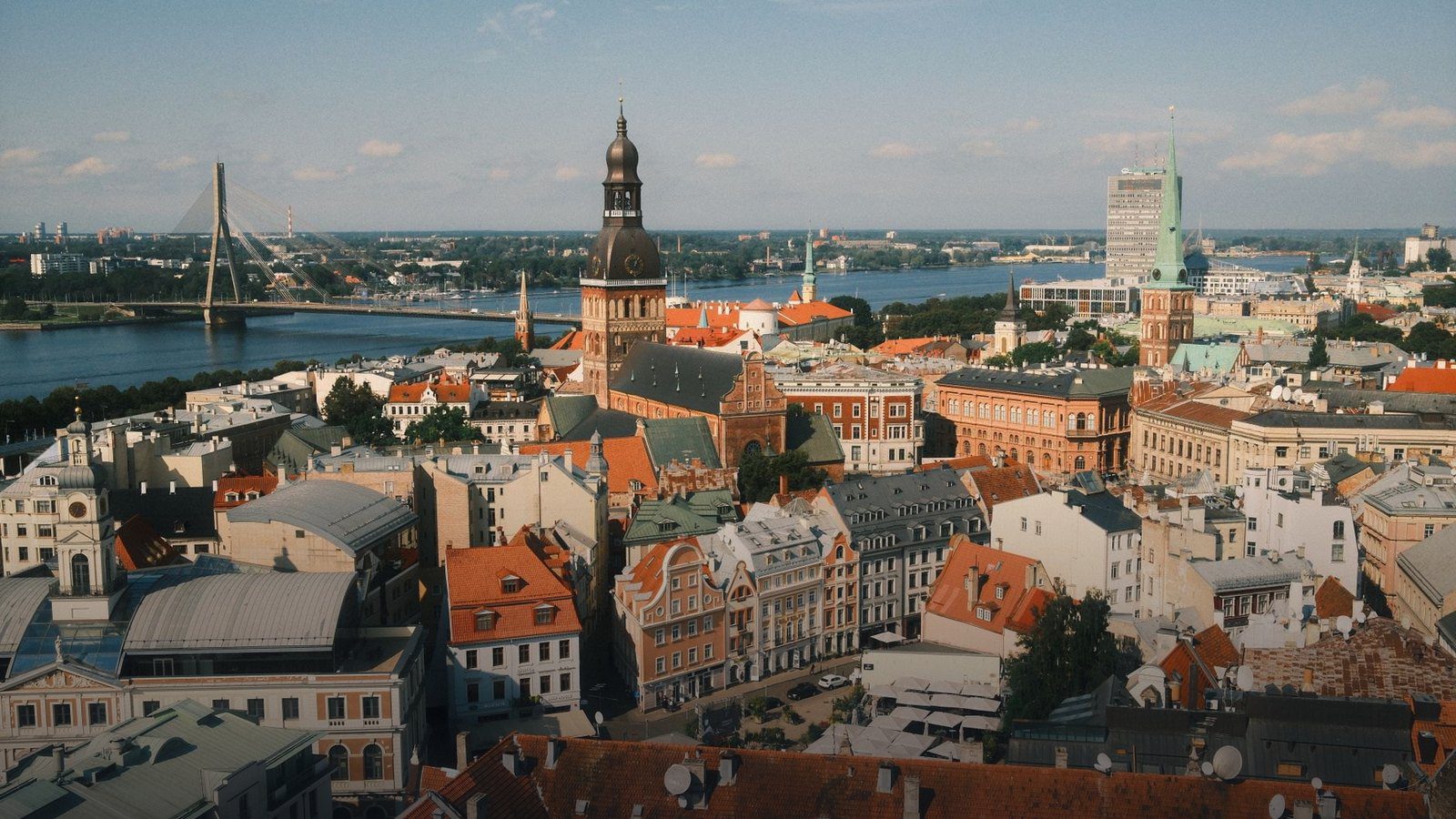 Wide view across the Daugava River toward the medieval church spires and historic red rooftops of Old Riga