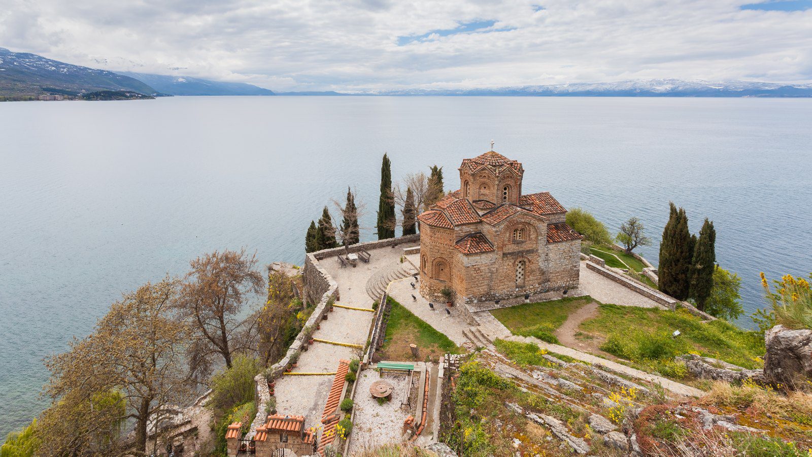 Scenic travel view of the medieval brick Church of St. John at Kaneo perched on a cliff overlooking deep blue Lake Ohrid in North Macedonia