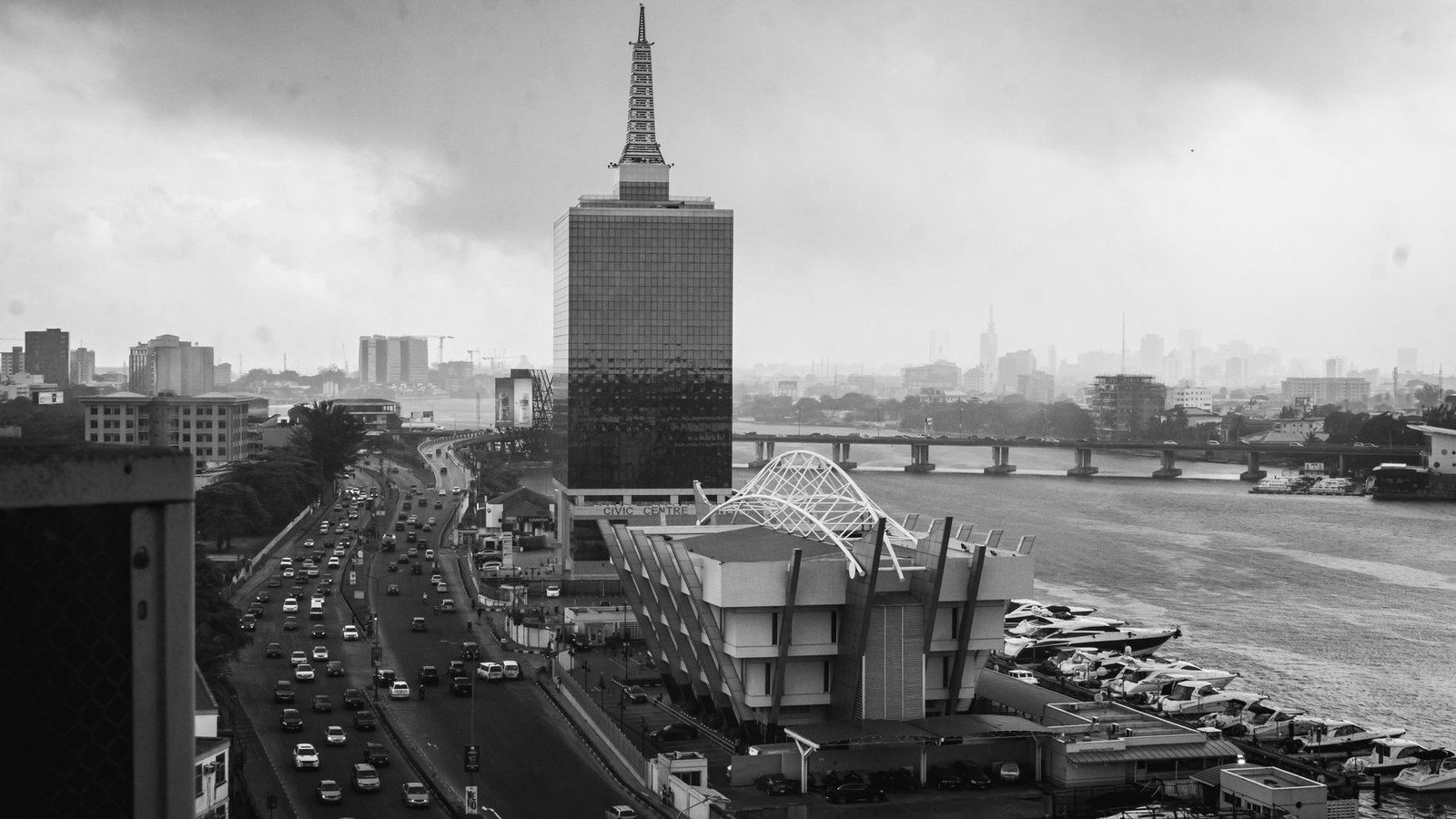 Black and white cityscape of Lagos with a prominent architectural structure and busy road.
