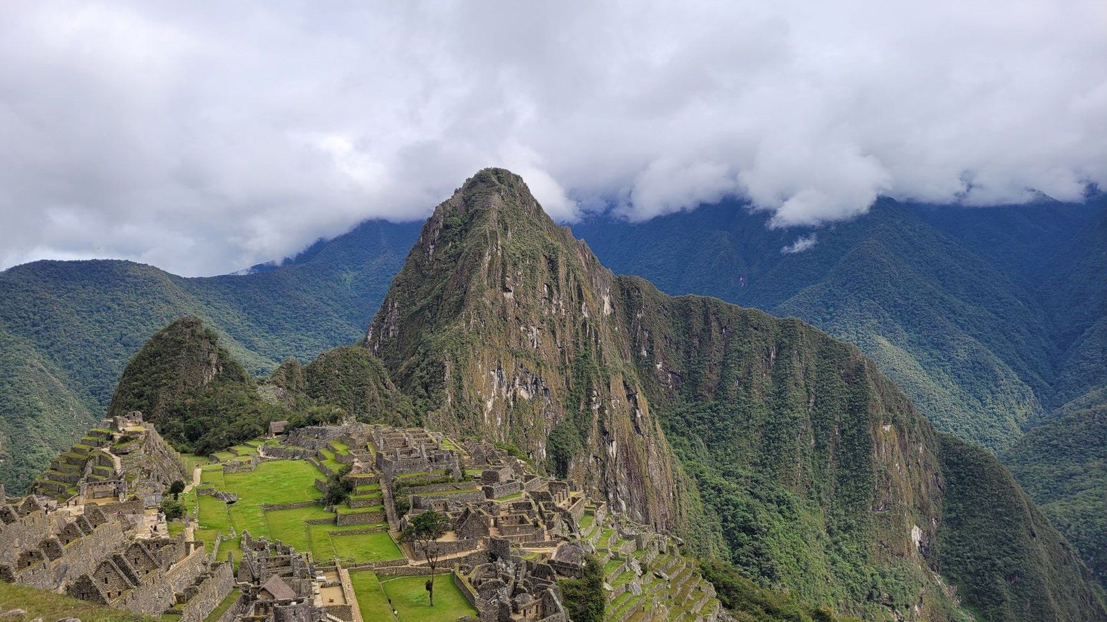 Stunning aerial view of the historic Machu Picchu in the Andes mountains, showcasing its ancient architecture and lush surroundings.