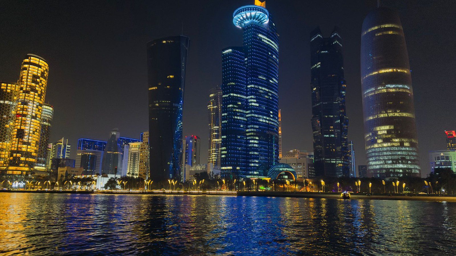 Captivating night scene of Doha's illuminated skyline reflecting on water in Qatar.