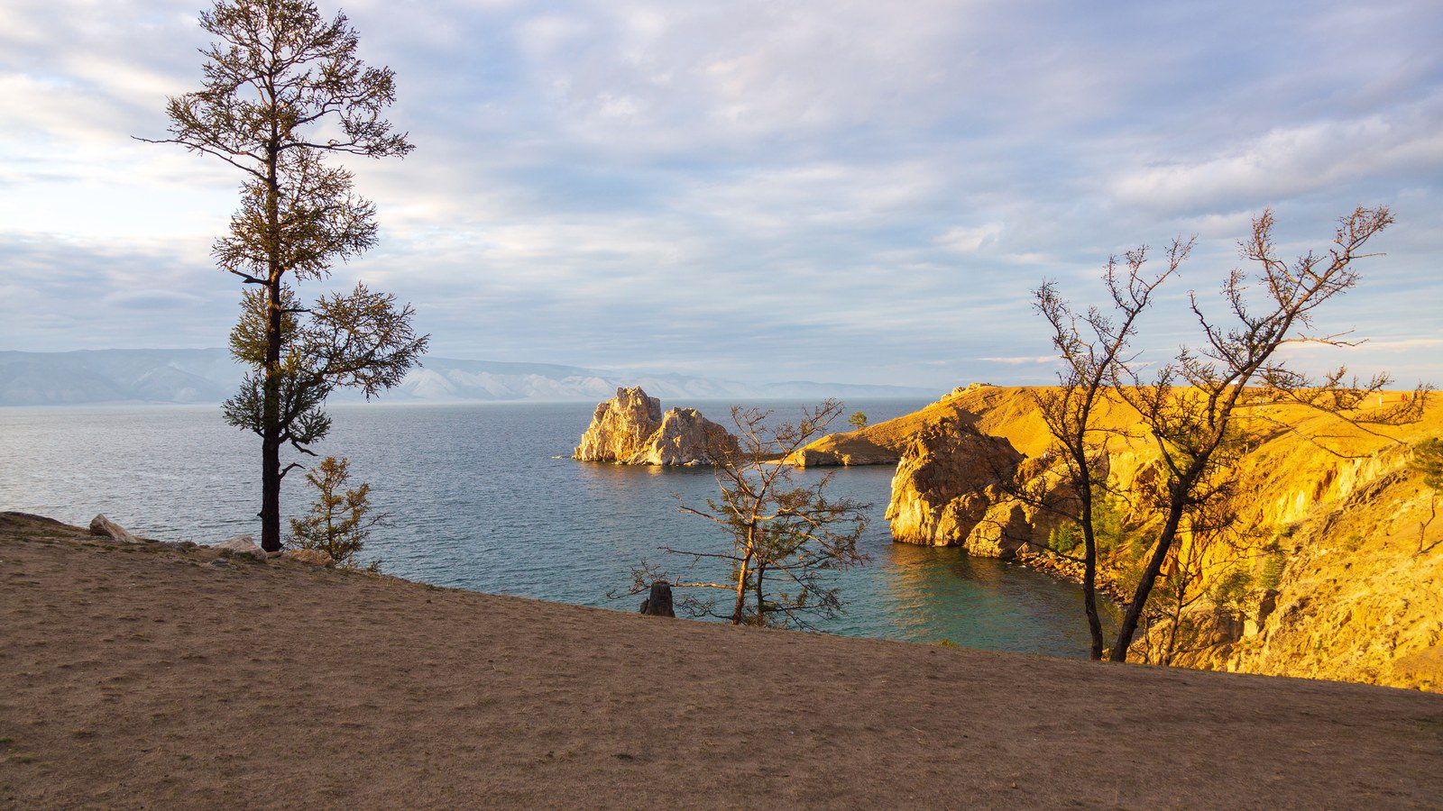 Iconic limestone crag of Cape Burhan on Olkhon Island surrounded by the clear blue expanse of Lake Baikal in Russia