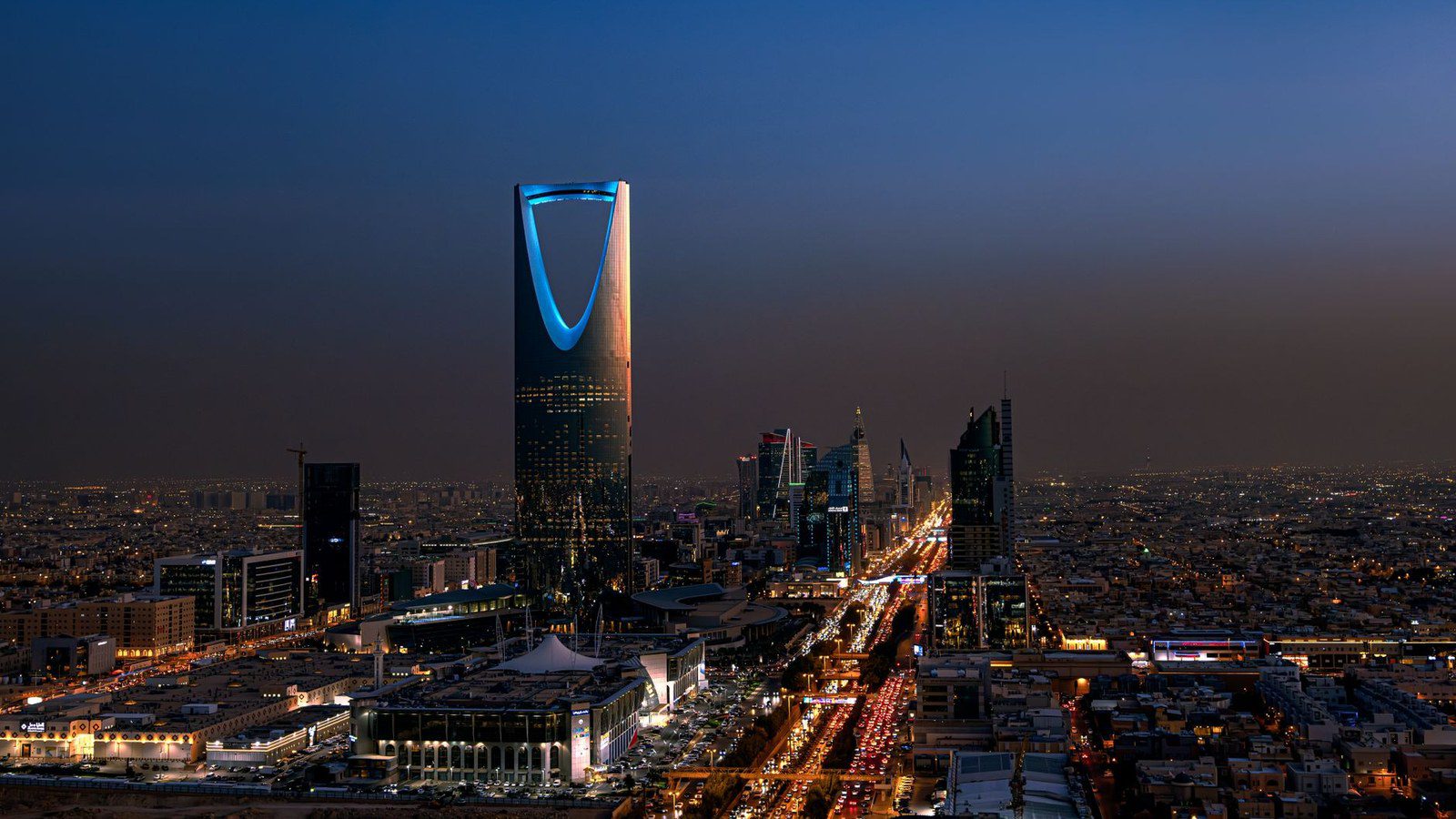 A breathtaking aerial view of Riyadh at night featuring the iconic Kingdom Centre Tower.