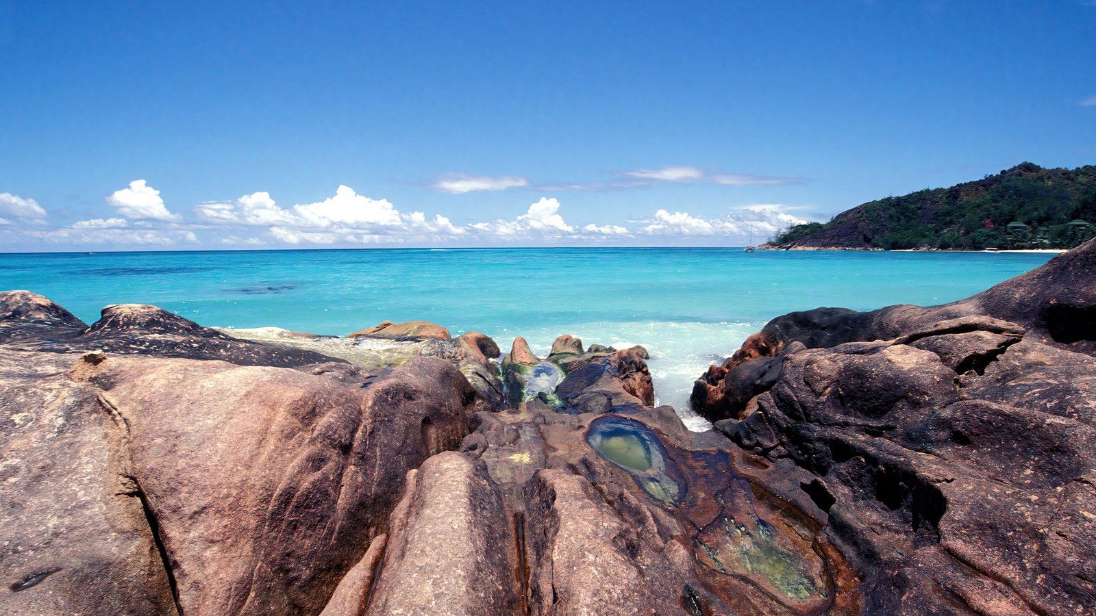 Iconic weathered granite rock formations rising from shallow turquoise lagoons in Seychelles