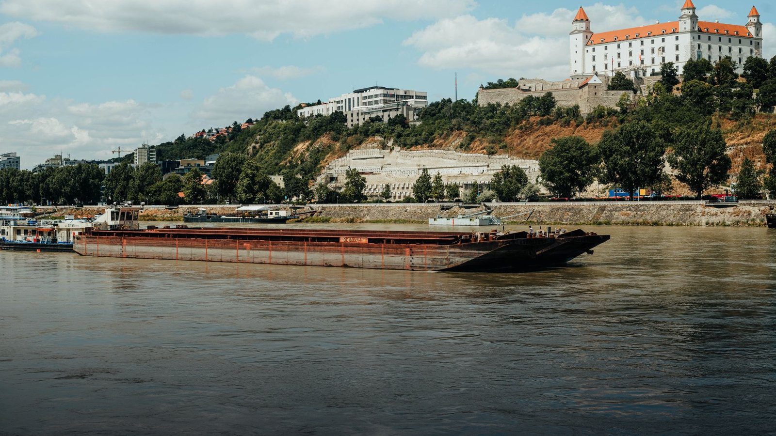 Rectangular stone Bratislava Castle with corner towers standing on a hill above the Danube River