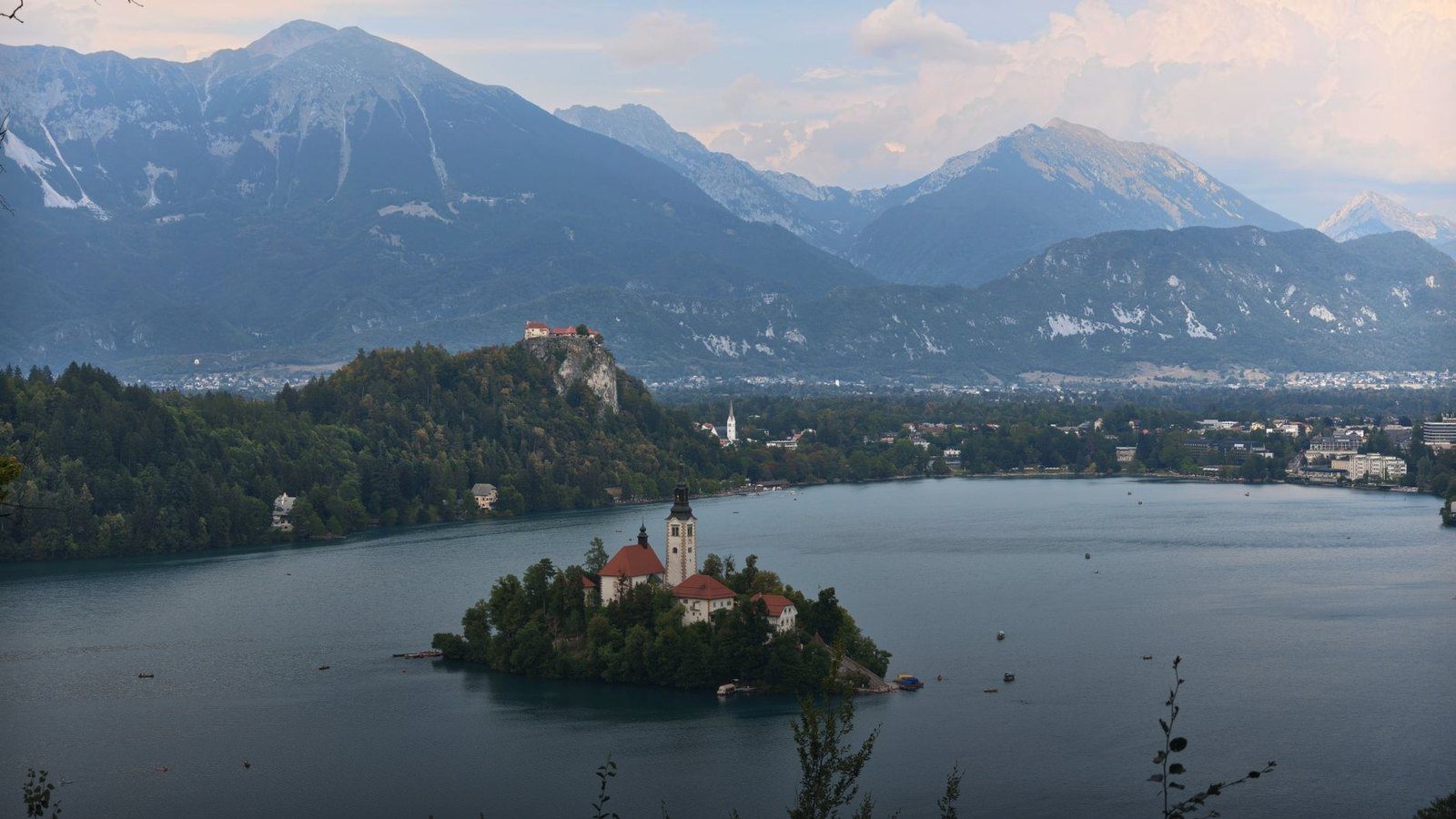 Scenic view across Lake Bled toward the small island with the Pilgrimage Church of the Assumption backed by Julian Alps