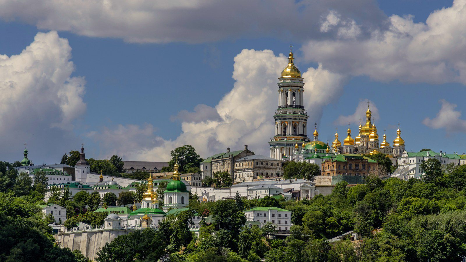 Golden domed baroque bell towers and churches of Kyiv Pechersk Lavra monastery complex overlooking the green hills in Ukraine