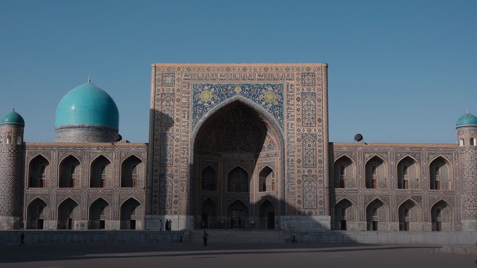 Turquoise mosaic tiled portal facades and towering minarets of the historic madrasahs on Registan Square in Samarkand